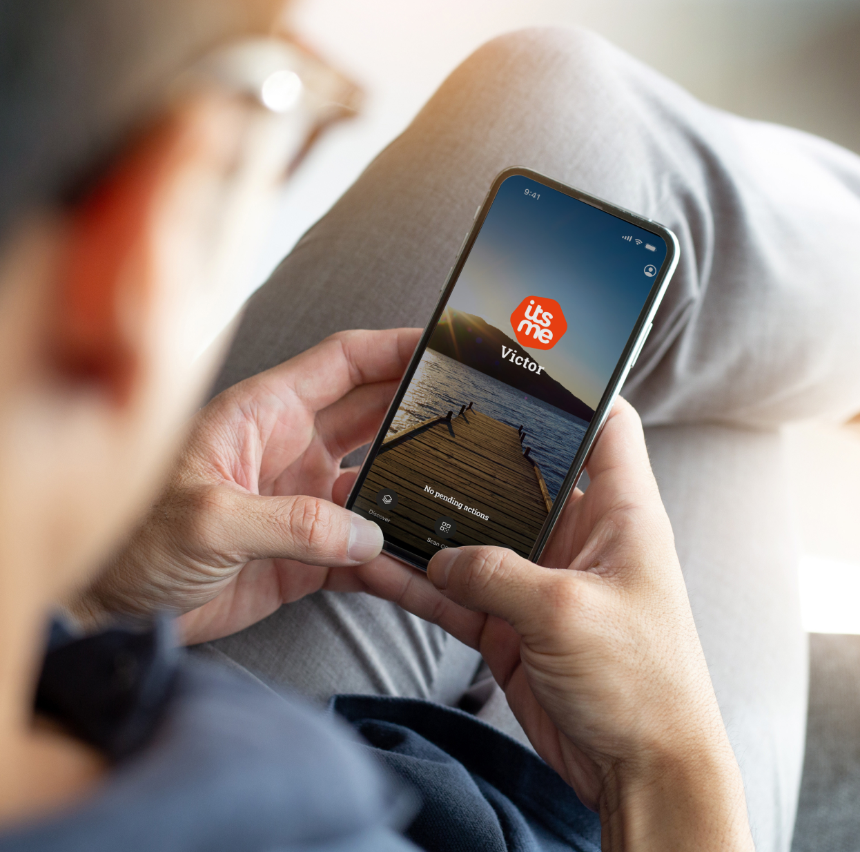 A man sitting down and holding a phone in his hands with the itsme app open